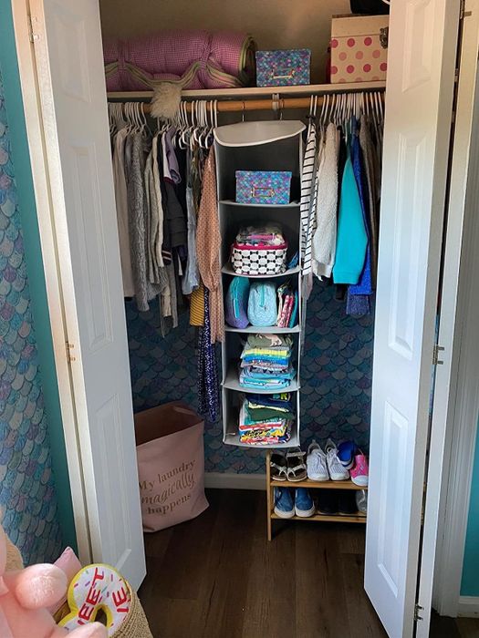 A reviewer's photo of the five-tier hanging shelf, complete with three mesh pockets on the side, neatly organized in a bedroom closet.