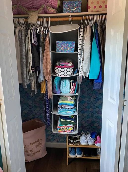 A reviewer's photo of the five-tier hanging shelf, complete with three mesh pockets on the side, neatly organized in a bedroom closet.