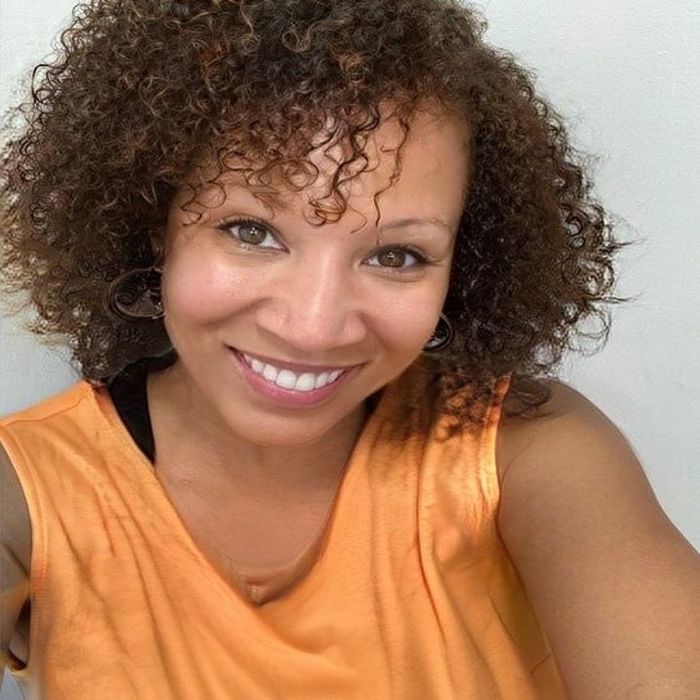 A reviewer with short coily hair showcasing her stunning results after using the set