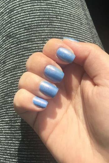 A review photo of a hand with light blue nails