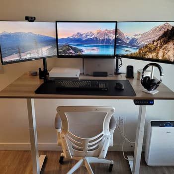 a reviewer’s photo of the desk equipped with three monitors