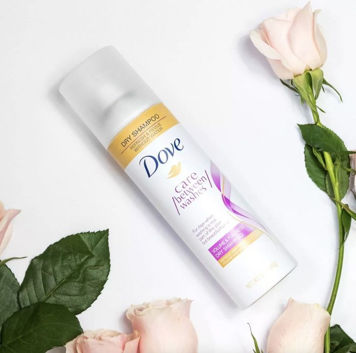 A bottle of dry shampoo alongside a bouquet of roses