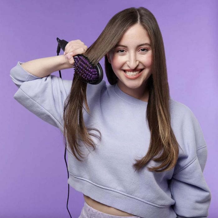 A woman using a straightening brush to style her hair
