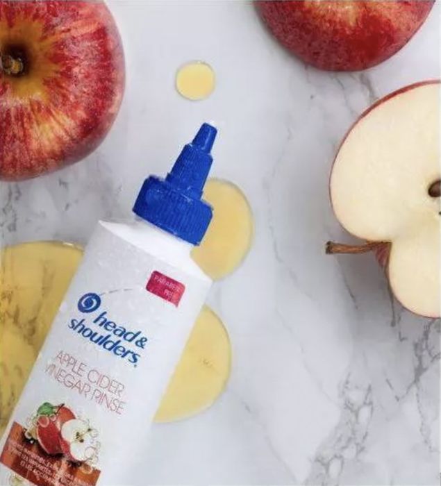 A bottle of hair rinse paired with a sliced apple