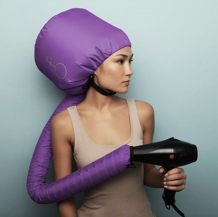 A woman using a hair dryer attachment with a blow dryer