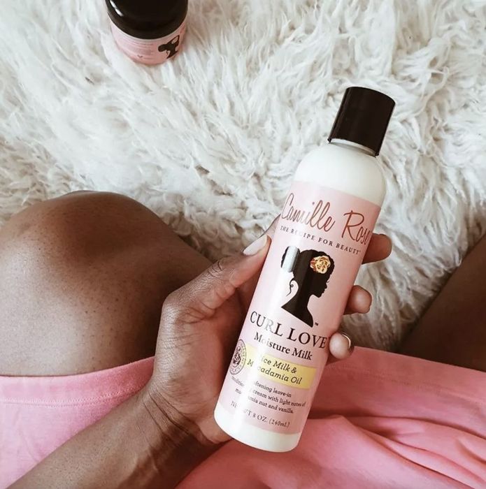 A woman holding a bottle of hair moisturizer