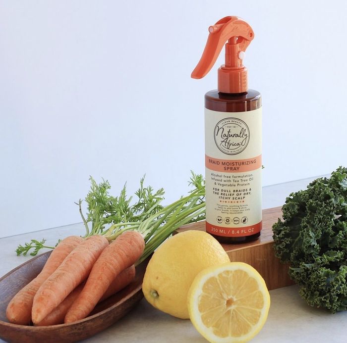 A bottle of braid spray alongside sliced lemons and carrots