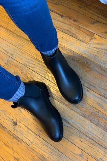 A reviewer photo of someone wearing the boots paired with thick gray socks and jeans