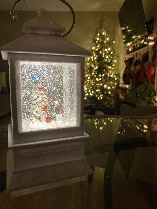 Reviewer photo of the glowing and snowing lantern placed in front of a beautifully decorated Christmas tree