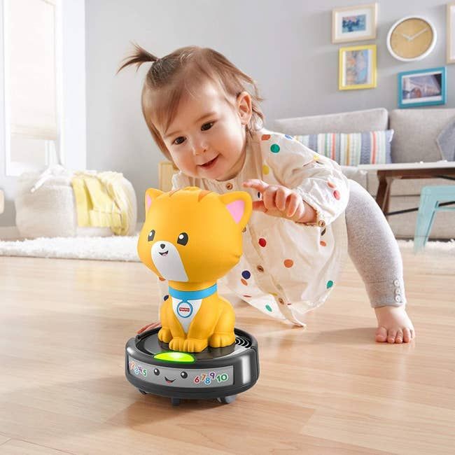 A child happily playing with the cat vacuum toy.