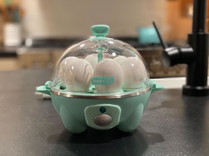 A reviewer's photo of the blue egg cooker with six eggs placed inside.