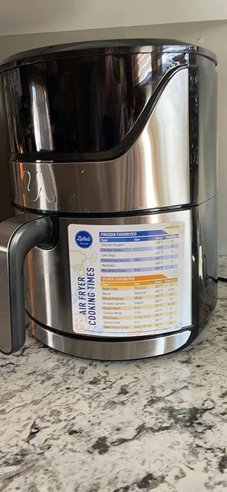 A reviewer's photo of an air fryer with the compact magnetic cheat sheet attached.