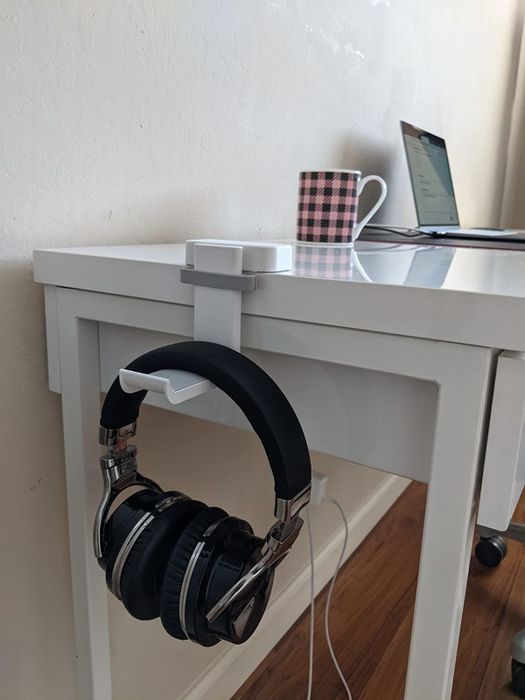 A reviewer showcases the white headphone holder secured to a desk.