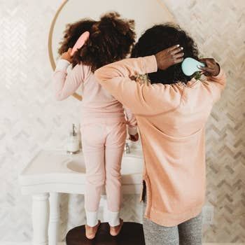 Both an adult and child are shown using the detangling brush on their hair, highlighting how versatile and effective it is for all ages and hair types.