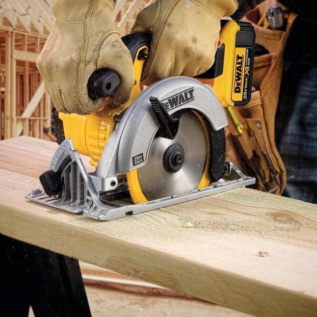 A person is cutting wood with a yellow and black cordless circular saw.