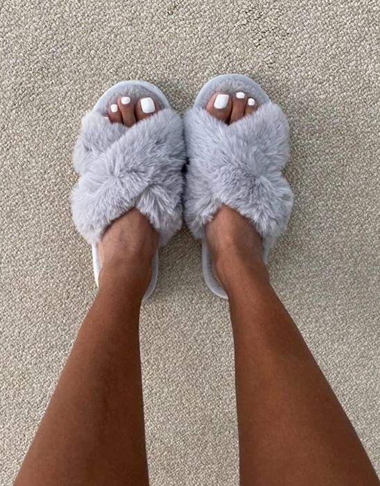 reviewer showcasing the gray fuzzy slippers
