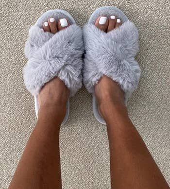 reviewer showcasing the gray fuzzy slippers