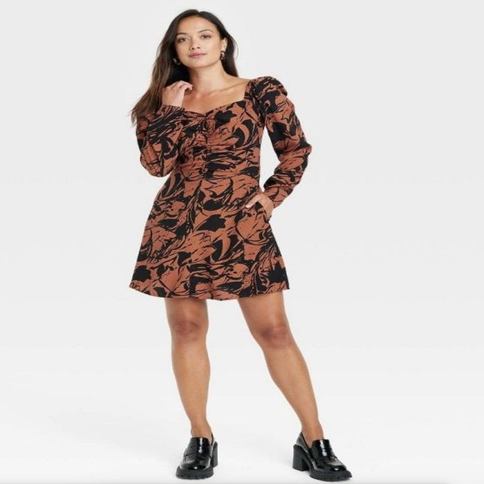 A model wearing a black and brown long sleeve ruched dress