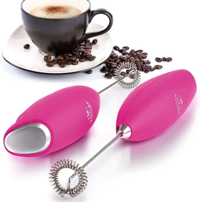 A pink frother placed next to a cup of coffee and a handful of coffee beans, ready to elevate the coffee experience