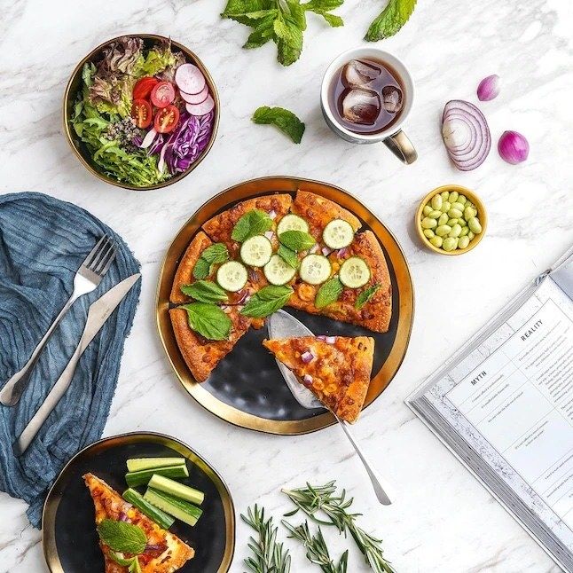 A dinnerware set featuring pizza, salad, and various other food items arranged on it.