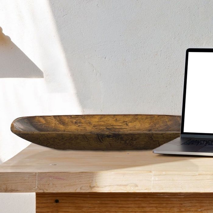 A wooden bowl positioned beside a laptop, adding a touch of elegance to the workspace
