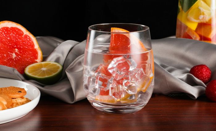 a glass filled with ice water and garnished with a slice of grapefruit