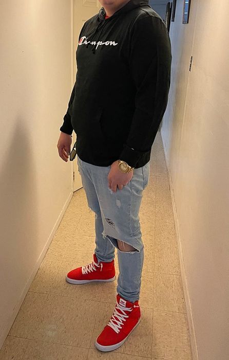 A reviewer pairing a black Champion hoodie with ripped jeans and red sneakers for a laid-back, sporty look.