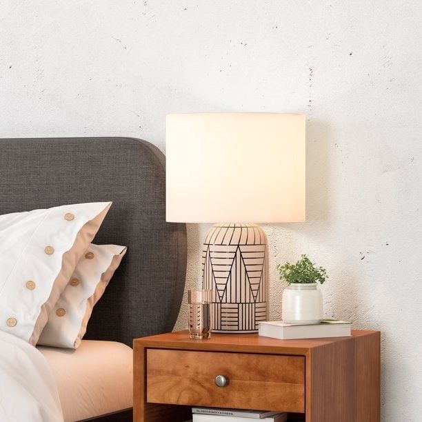 A table lamp placed on a wooden nightstand beside a bed