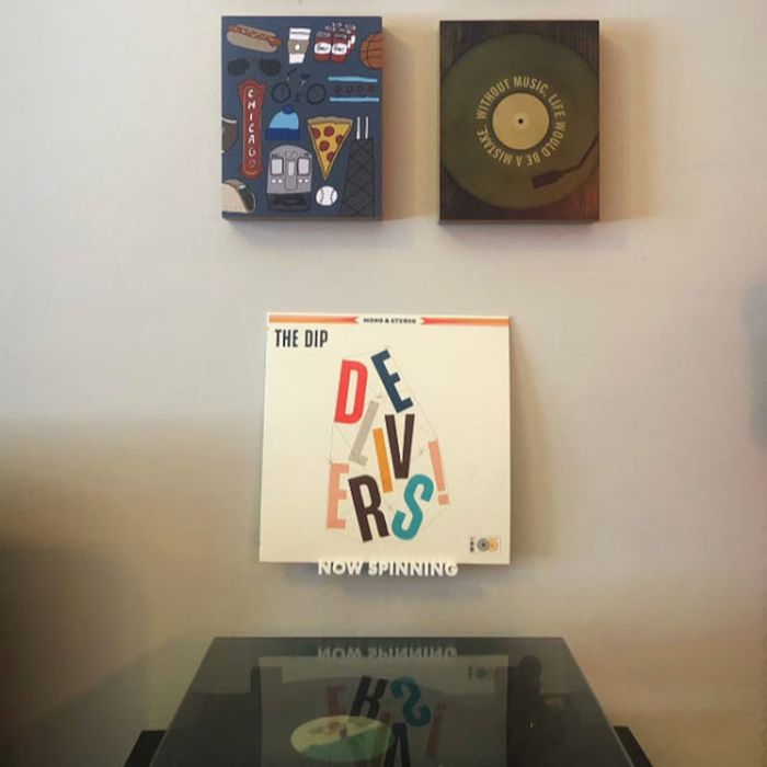 A mounted shelf above a record player, holding a vinyl by The Dip.