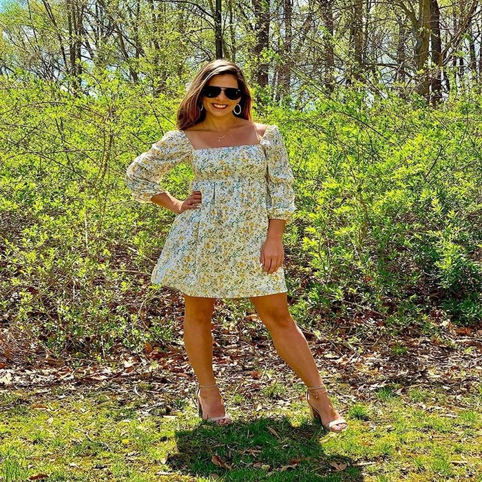 A reviewer posing in the floral print dress paired with heels