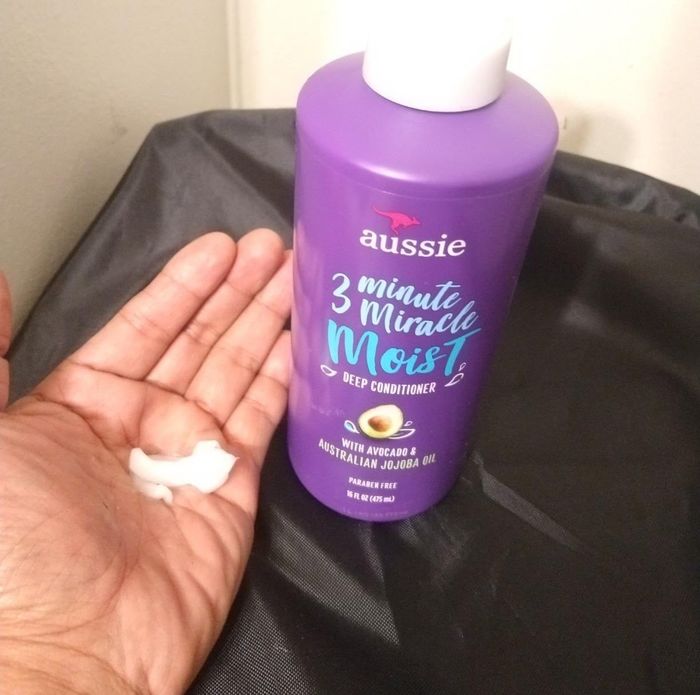 a hand holding a small amount of the conditioner next to the bottle