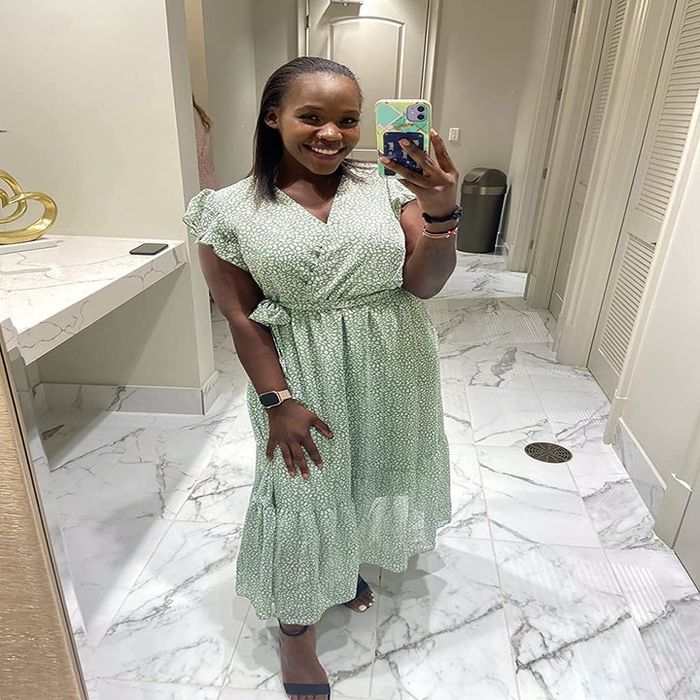 A reviewer wearing the same dress in a green and white polka dot pattern, paired with black sandals