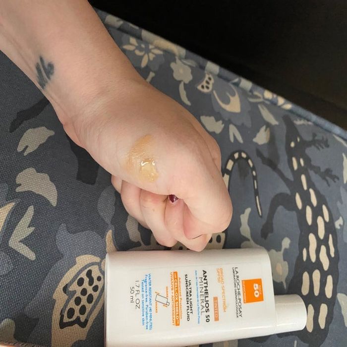 A reviewer applying the sunscreen to their face