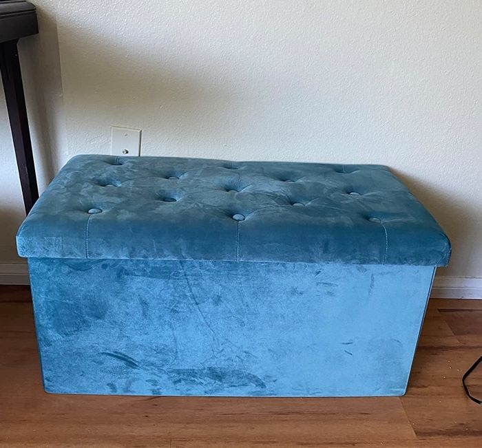 A reviewer’s photo showcasing the large blue velvet ottoman in their living space