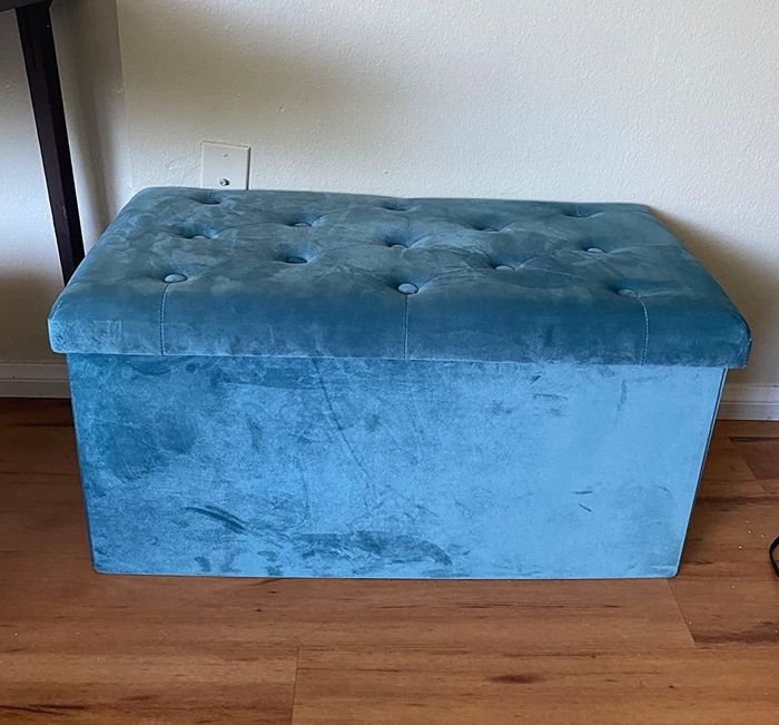 A reviewer’s photo showcasing the large blue velvet ottoman in their living space