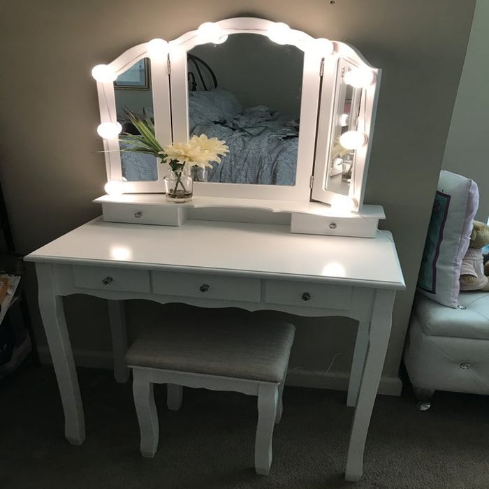 A reviewer's photo of the white vanity table with the lightbulbs shining bright