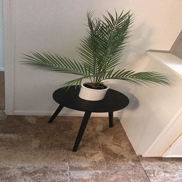 A reviewer’s photo showing the black side table with a plant on top, styled in their space