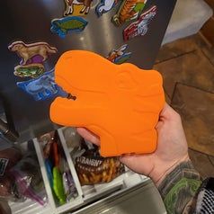 A reviewer's photo showcasing an orange dinosaur-shaped ice pack, adding a fun touch to keeping items cool.