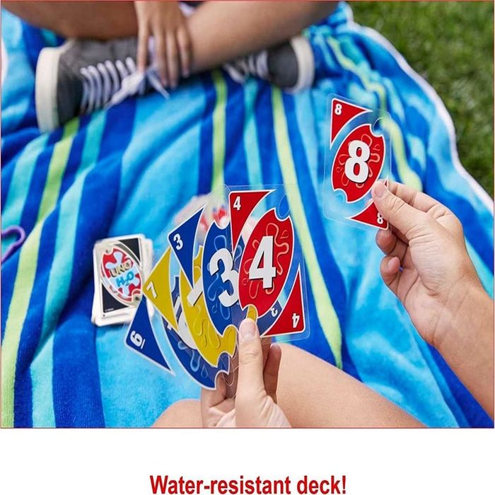 Models sitting outdoors on a towel, holding waterproof playing cards in their hands