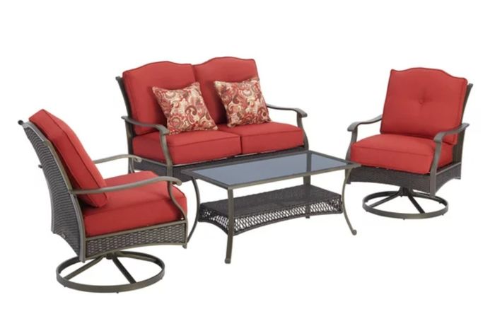 the red cushioned chairs, sofa, and the elegant glass-topped wicker coffee table