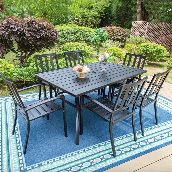 the black steel dining table surrounded by six matching chairs, placed on a well-appointed patio