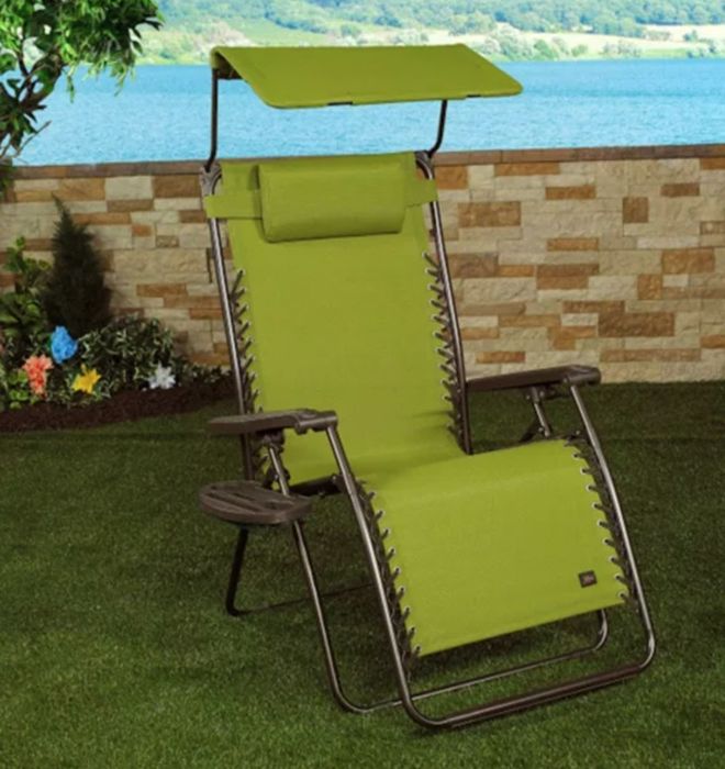 a comfortable green zero gravity chair with a canopy, placed in a tastefully decorated backyard space