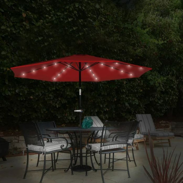 the red umbrella, with lights hanging underneath, positioned over a dining table on a patio
