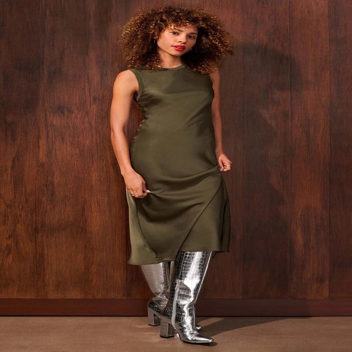 A model wearing the silver snake-print boots paired with a green maxi dress