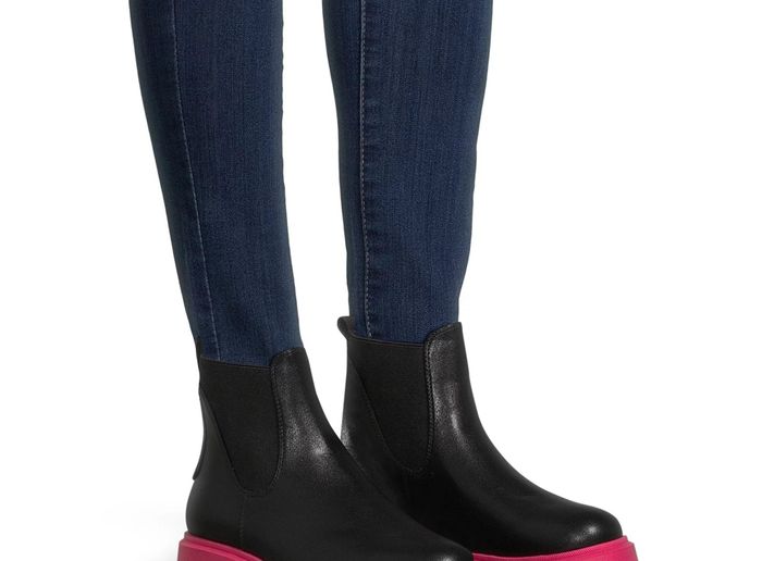 A model wearing the black boots featuring bold hot pink soles