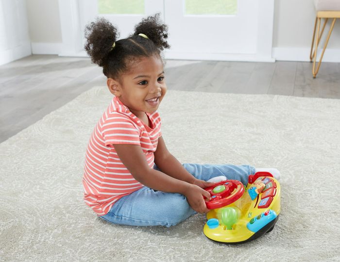 A girl playing with a toy steering wheel, fully immersed in her driving adventure.