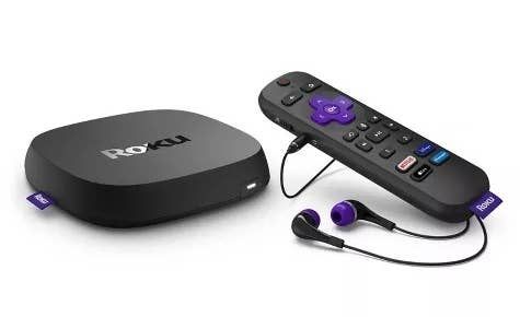 A Roku streaming device placed beside its remote control and headphones, perfect for private listening