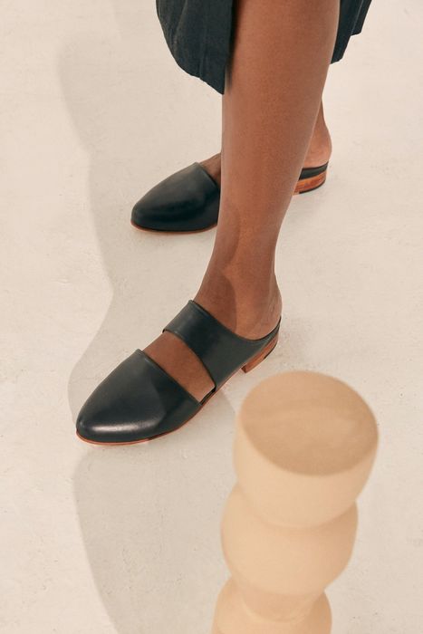 A model showcasing the pointed-toe, open-back flats with a unique cutout detail across the top of the foot.