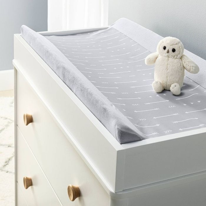 A baby changing table featuring a soft, patterned mat and a stuffed owl toy placed on top