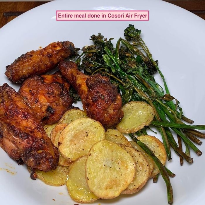 A plate featuring roasted chicken wings, crispy potato slices, and broccolini. Text: 